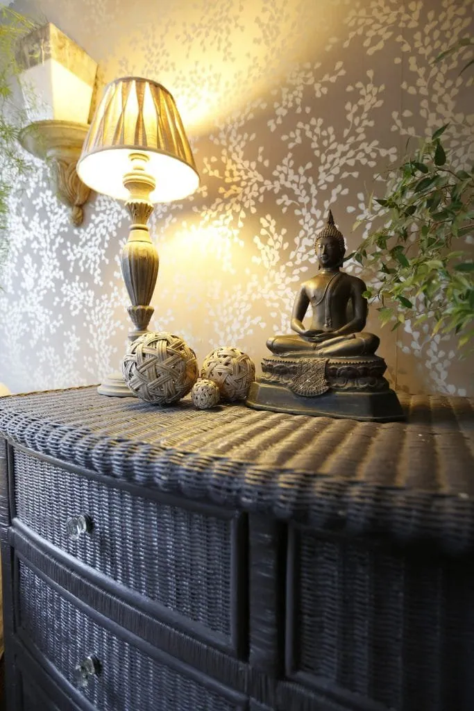 Charcoal wicker chest of drawers with a carved lamp, woven balls and a Buddha statuette