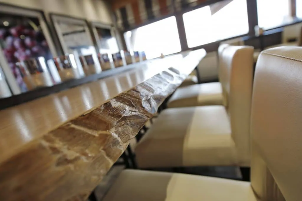 Long live-edge wooden table lined with ivory bar chairs