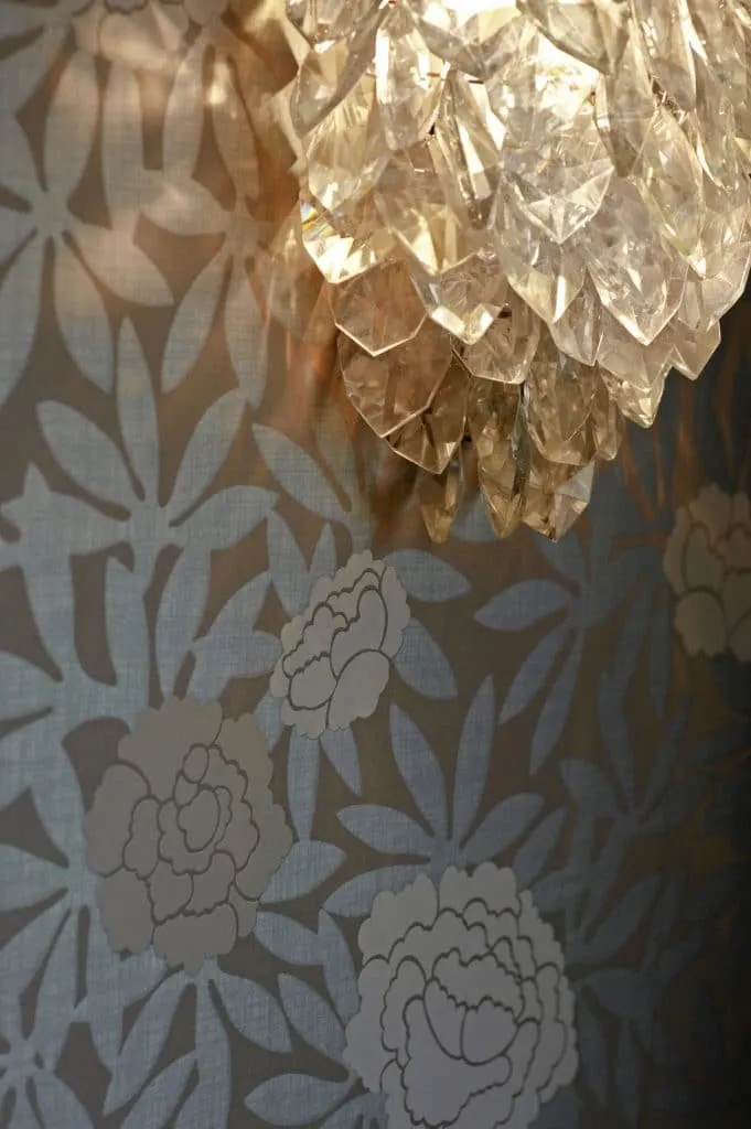 Detail of a crystal wall light on the bedroom’s floral wallpaper