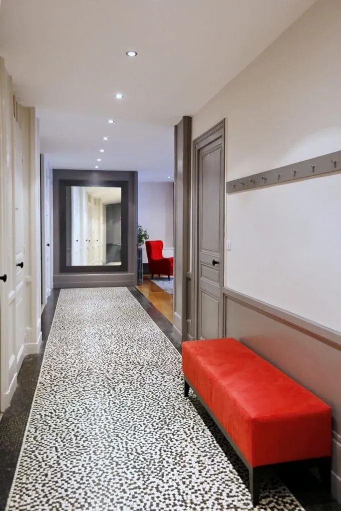 Black and white mosaic hallway leading to the living room, with a red bench, Grenoble apartment