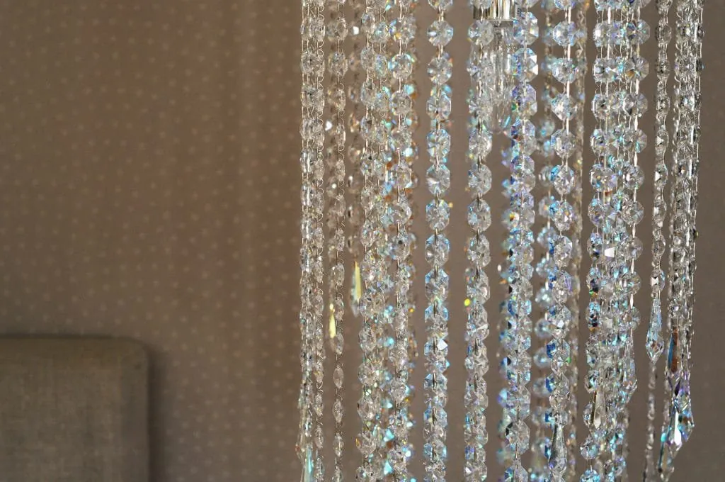Close-up of a crystal pendant light against the bedroom’s textured wallpaper