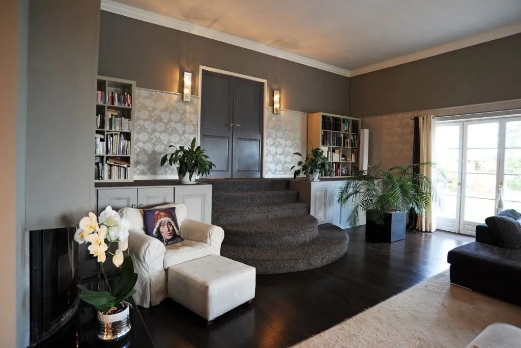 Large living room in a Nord Isère family home: curved steps, bookshelves and white armchair