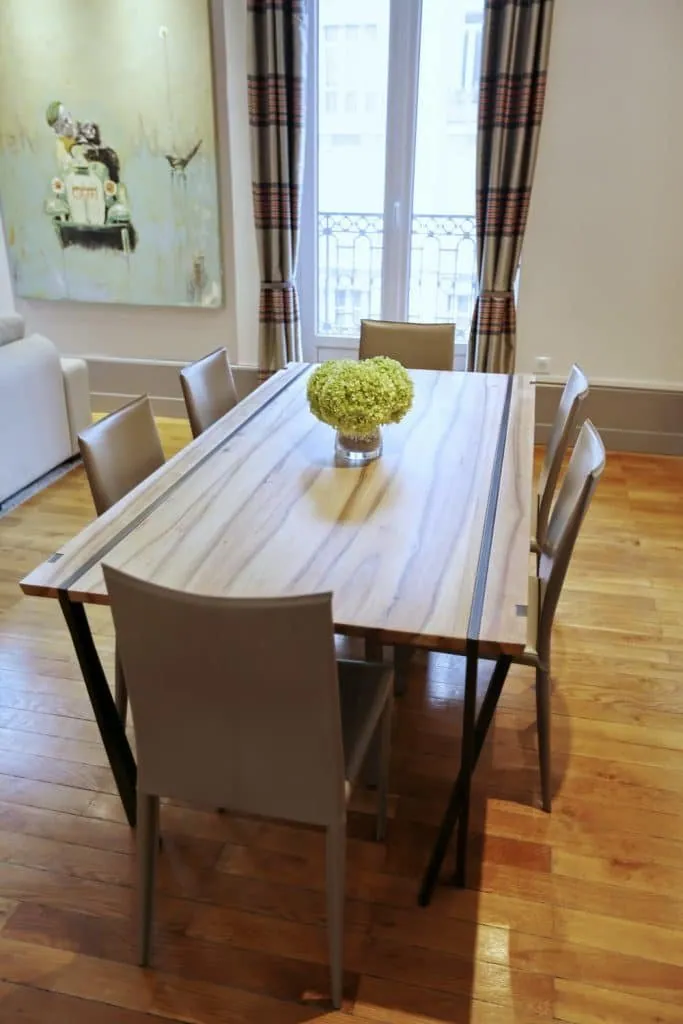 Bespoke walnut dining table with grey chairs and a hydrangea bouquet, Grenoble apartment