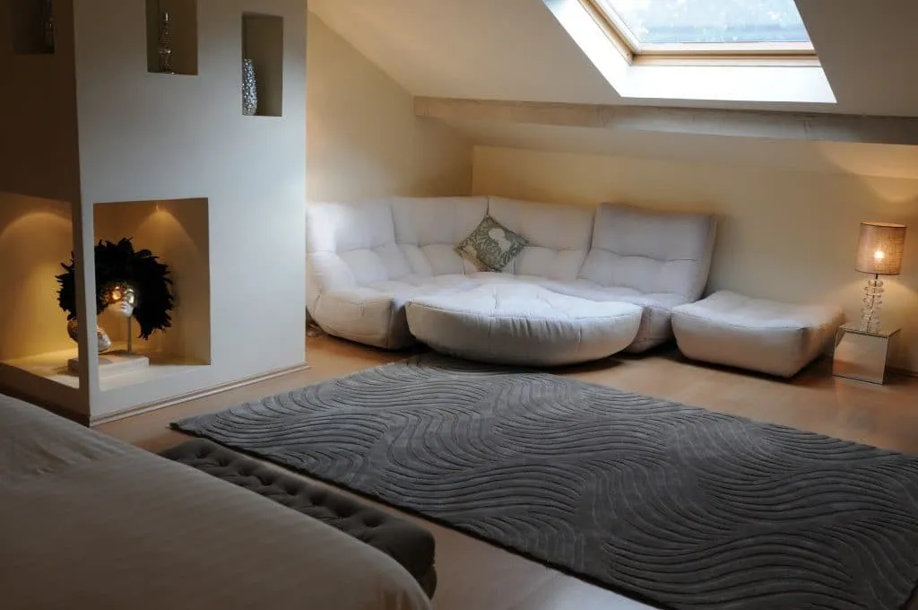 After the renovation, a large white corner sofa, grey rug and lit wall niches
