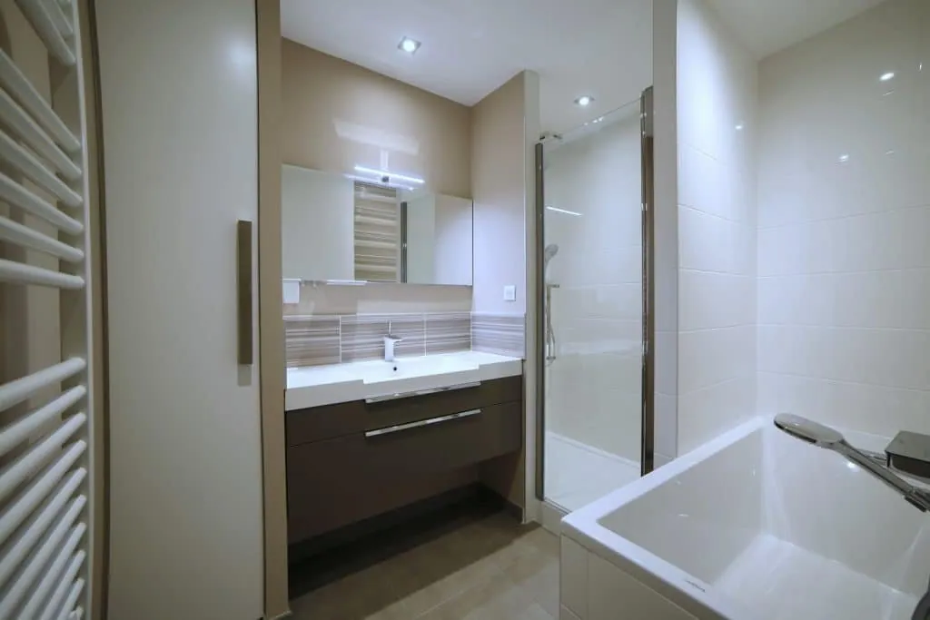 Bathroom with dark brown vanity unit, glass shower and bathtub, Grenoble apartment