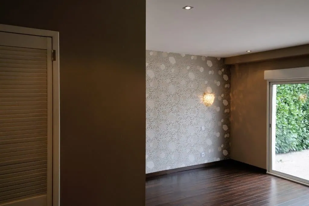 Former garage turned bedroom, sliding glass door onto the garden and floral wallpaper