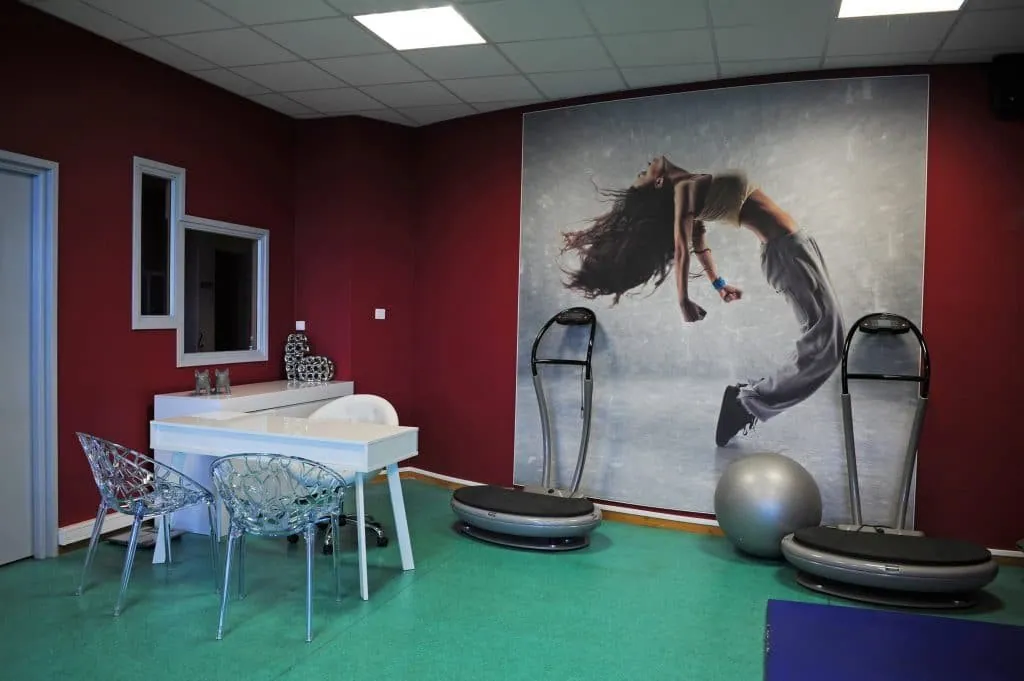 Giant dancer print on a red wall, vibration plates and a desk with transparent chairs