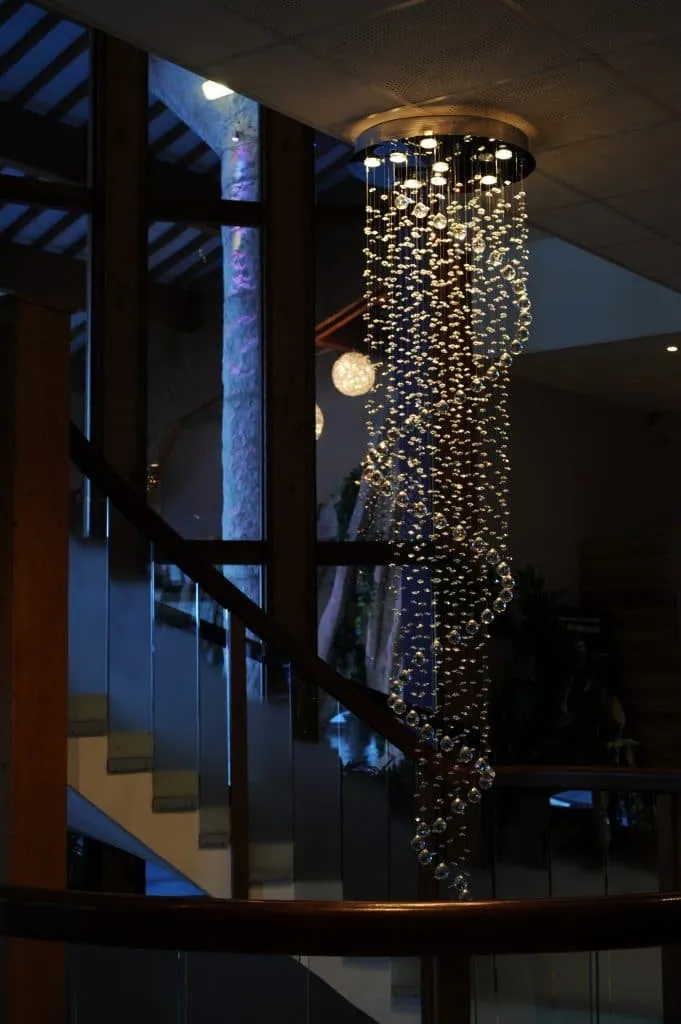 Cascading crystal chandelier in the spa stairwell, wooden handrail and glass balustrade