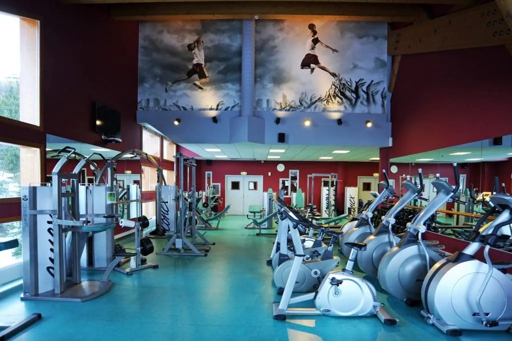 Gym with red walls, cardio machines and giant prints of basketball players