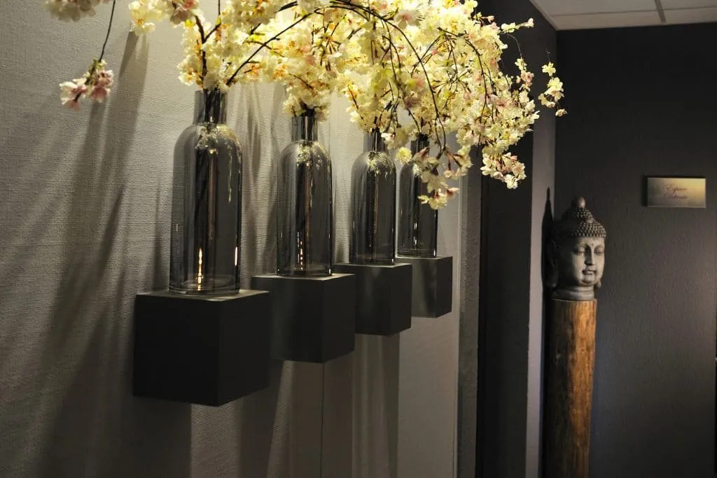 Corridor after the redesign, smoked glass vases on wall-mounted cubes, blossom branches, Buddha head