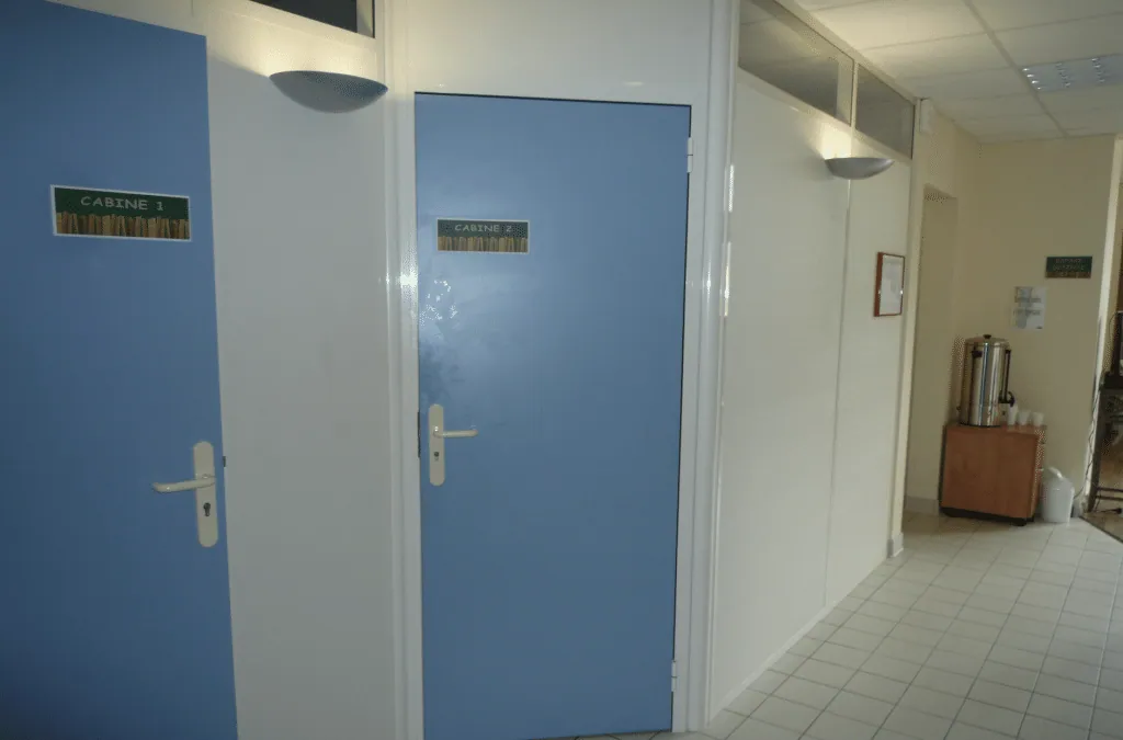 Corridor before the redesign, blue treatment room doors, white walls and pale floor tiles
