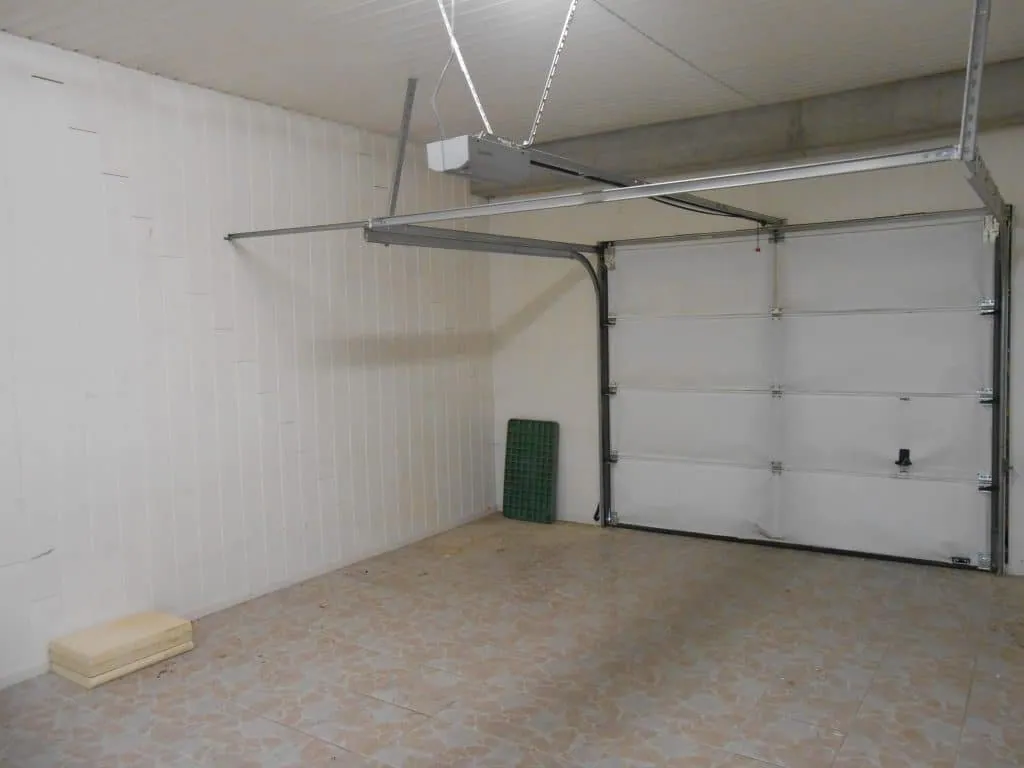 The garage before its conversion, with sectional door, white walls and tiled floor
