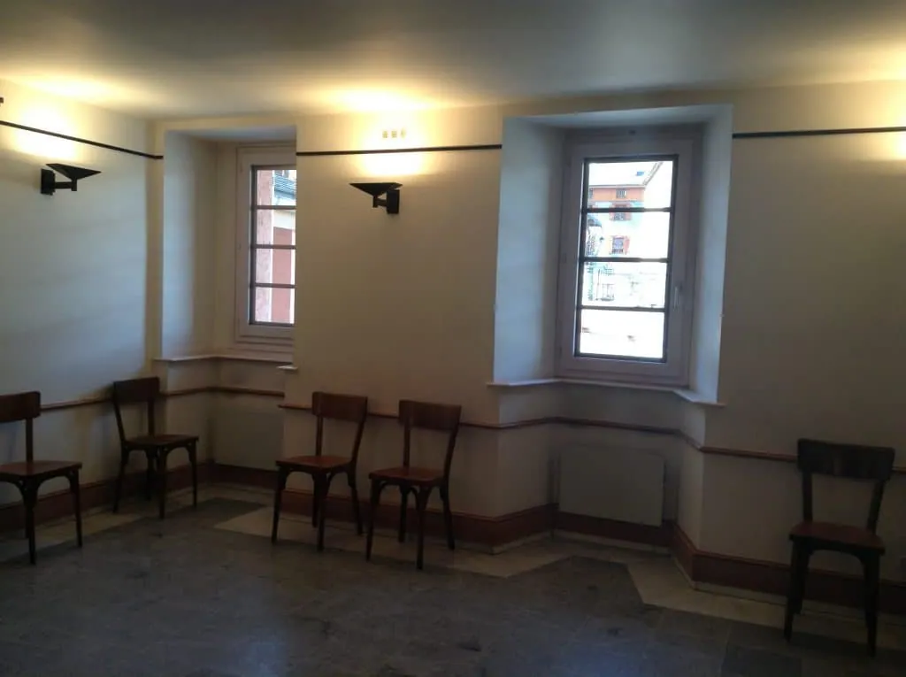 Before the project, the wedding hall with white walls, recessed windows and bistro chairs