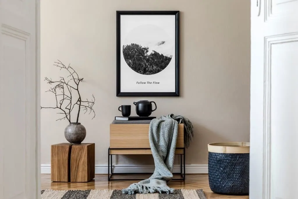 Minimalist interior design with beige walls, a light wood cabinet, a grey throw and dry branches