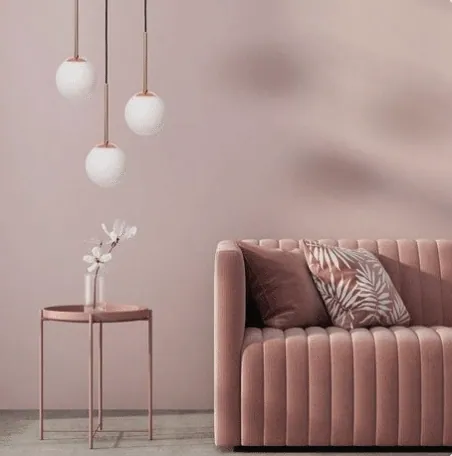 Dusty pink living room with a velvet sofa, side table and three globe pendant lights