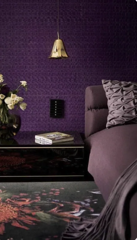 Purple interior with a textured wall, gold pendant light, black lacquered table and white flowers
