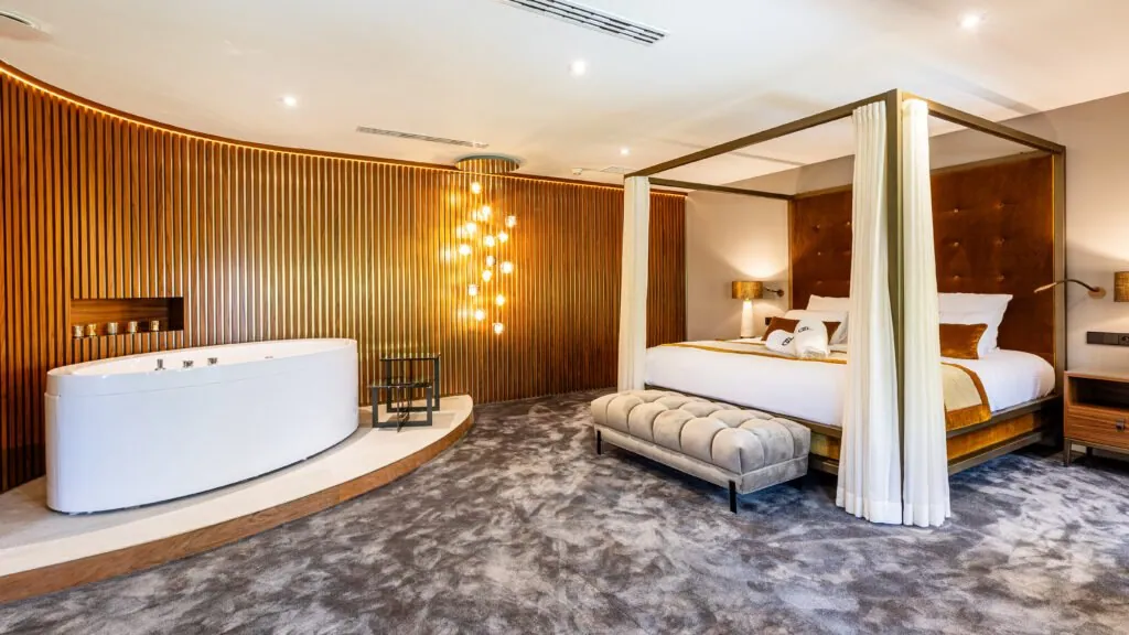 Canopy bed, bathtub and curved wooden slat wall at the Domaine de Dolomieu