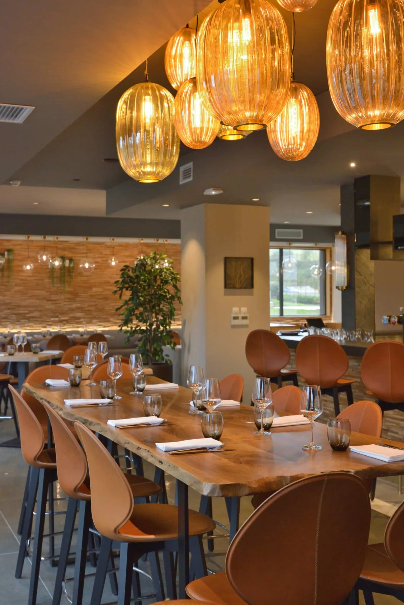 Long live-edge wooden high table beneath the amber pendant lights at Le 205