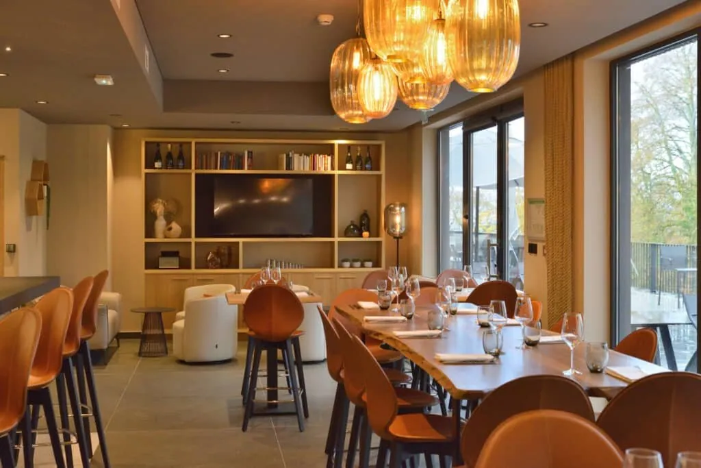 Lounge corner at Le 205 with light wood shelving, white armchairs and a high table