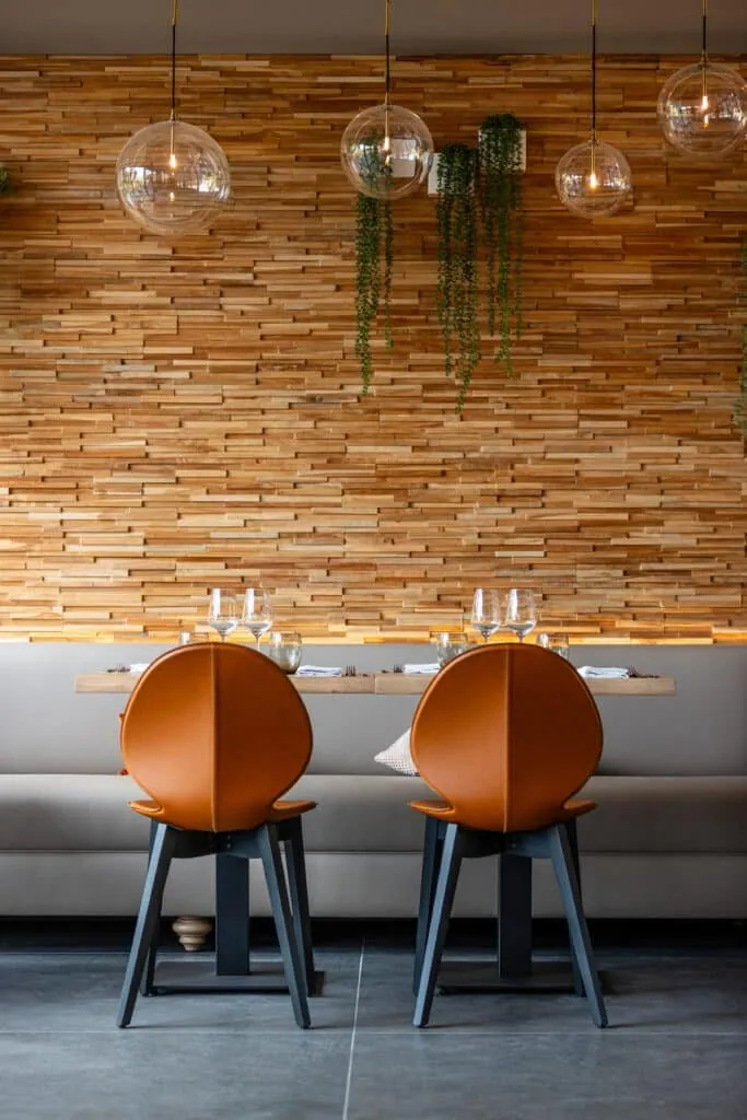 Deux chaises en cuir caramel vues de dos devant une table dressée au restaurant Le 205