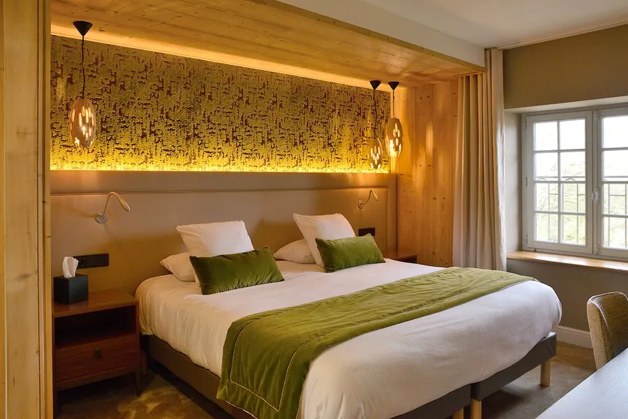 Chambre lambrissée, tête de lit éclairée et plaid vert
