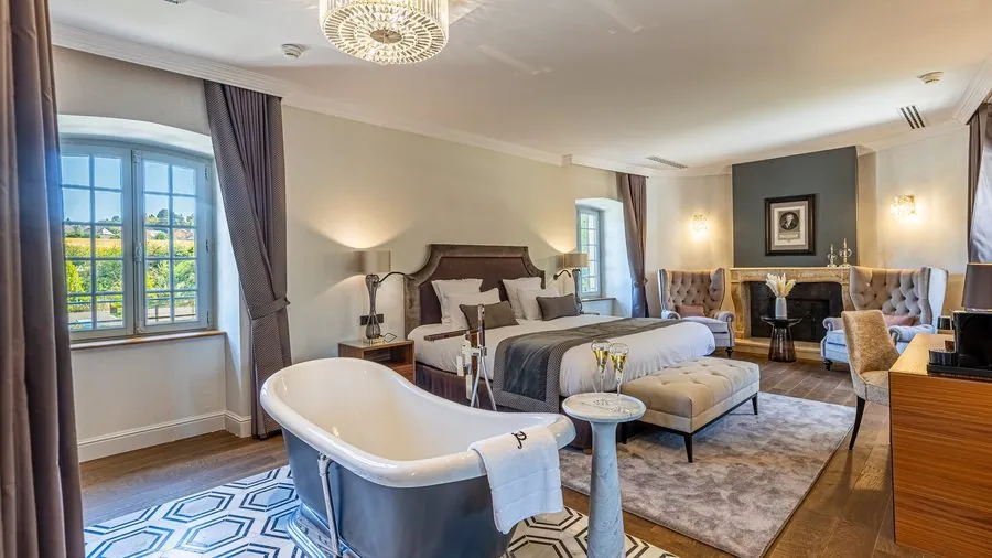 Chambre avec baignoire îlot et cheminée en pierre